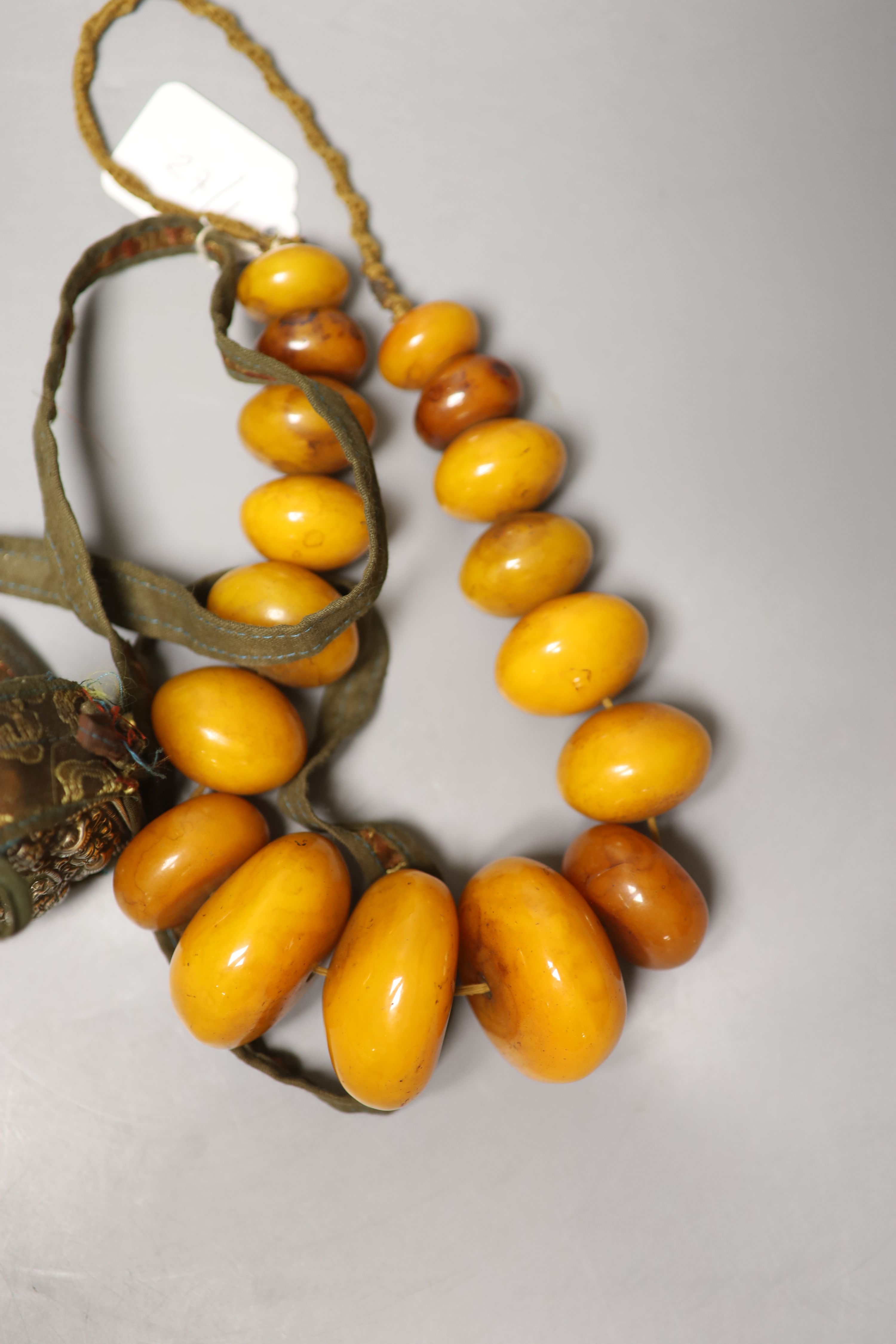 An early 20th century Tibetan and white metal portable shrine and a simulated amber Buddhist rosary